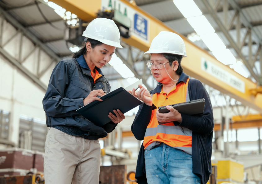 IITH workers in a factory setting wearing safety gear and discussing operations